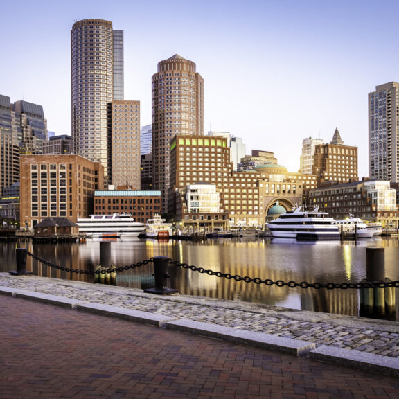 The Boston Harbor and Financial district in Boston, Massachusetts, USA at sunrise showcasing its mix of contemporary and historic buildings.